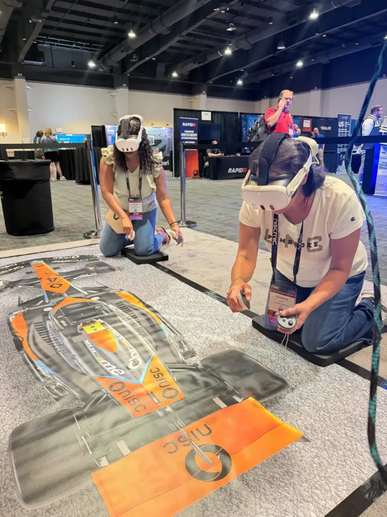 Two players in VR headsets racing head-to-head in the pit stop challenge at a Las Vegas trade show