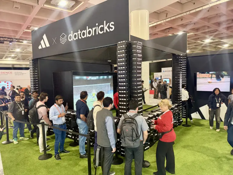 Attendees lining up at the adidas x Databricks soccer simulator booth built from shoe boxes at Data + AI Summit 2026, Moscone Center, San Francisco