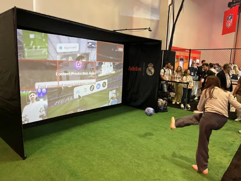 Attendee kicking a ball at the Adobe and Real Madrid digital shootout screen while others watch at Adobe Summit 2026, Venetian Expo, Las Vegas