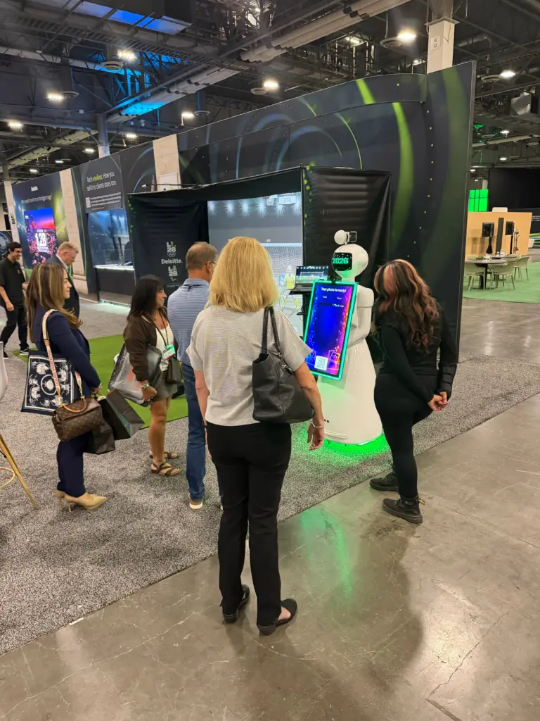 Guests trying the AI photo booth robot in front of the Deloitte sport simulator at the Venetian Expo, Las Vegas