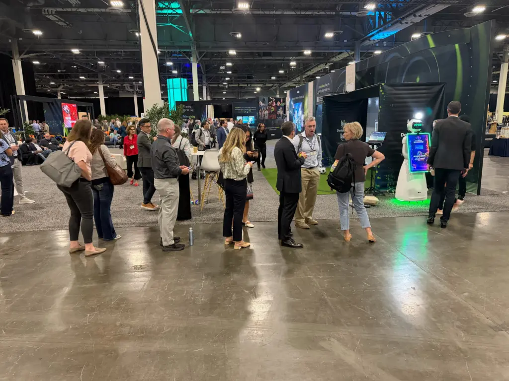 Attendees gathering near the Deloitte-branded sport simulator and AI photo booth at the Venetian Expo in Las Vegas