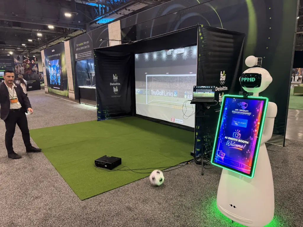 Deloitte LA28 branded soccer simulator and the AI photo booth robot set up side by side at the Venetian Expo, Las Vegas