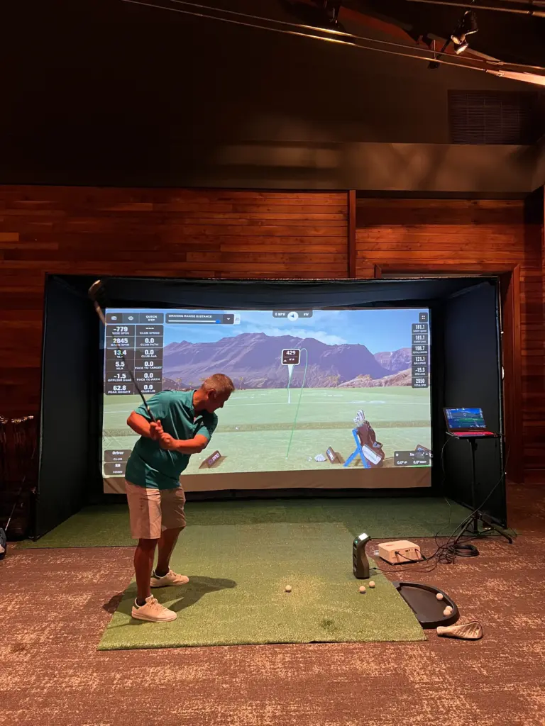 Golfer swinging a driver at a golf simulator during a corporate innovation event in San Antonio