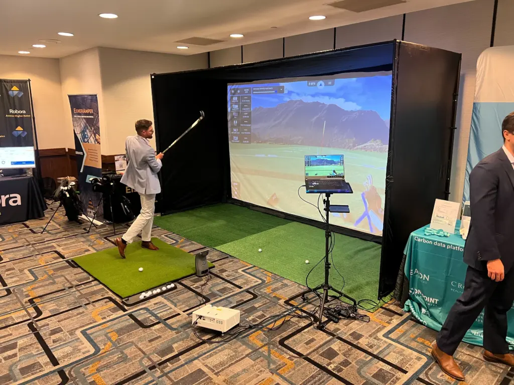 Guest following through on a swing at the EisnerAmper golf simulator in a New York conference exhibit hall