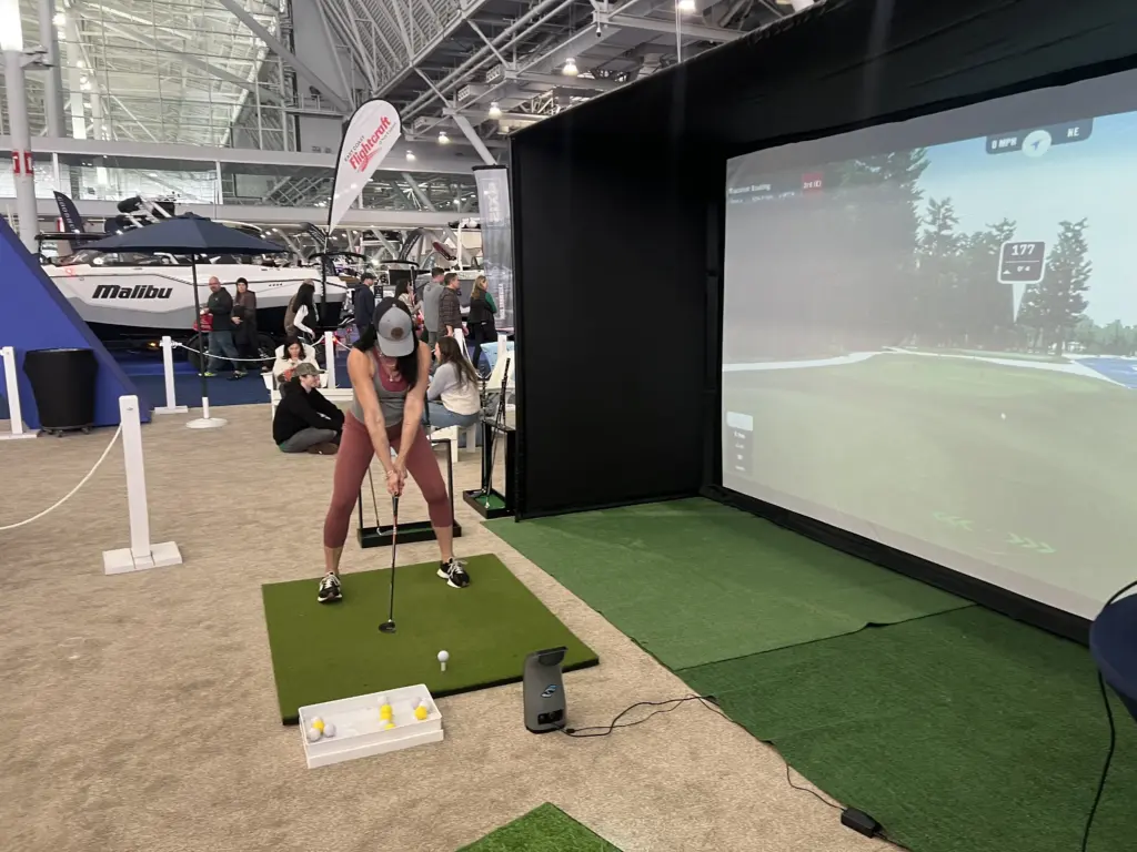 Guest lining up a drive at the golf simulator at the New England Boat Show, Boston Convention and Exhibition Center