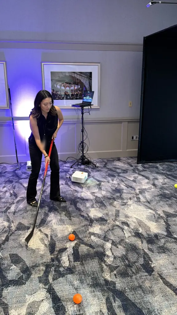 Guest stickhandling a ball at the hockey simulator during an indoor event