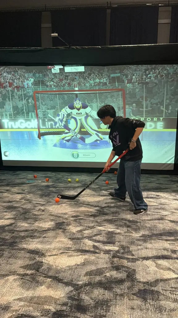 Player taking a slap shot at the hockey simulator goalie on the big screen