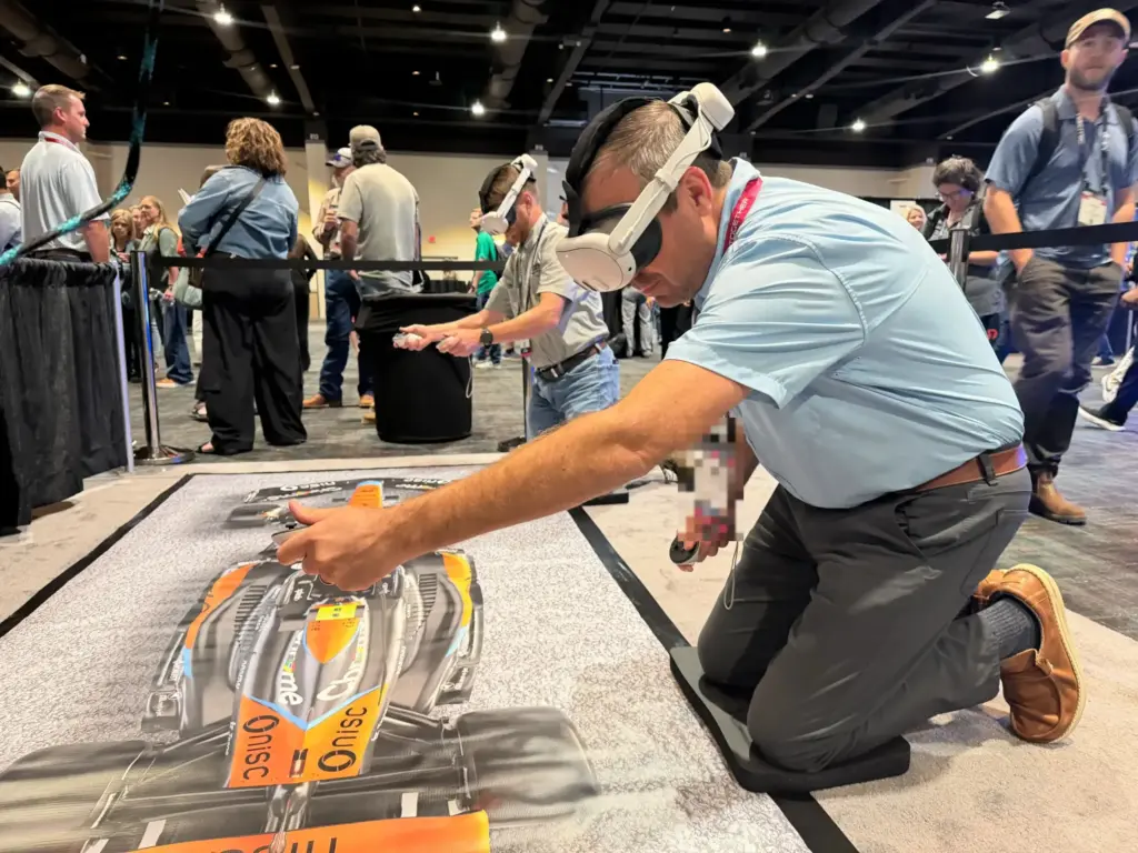Attendee in a VR headset working the virtual impact gun on the pit lane mat during the pit stop challenge at NISC Member Information Conference 2026, MGM Grand, Las Vegas