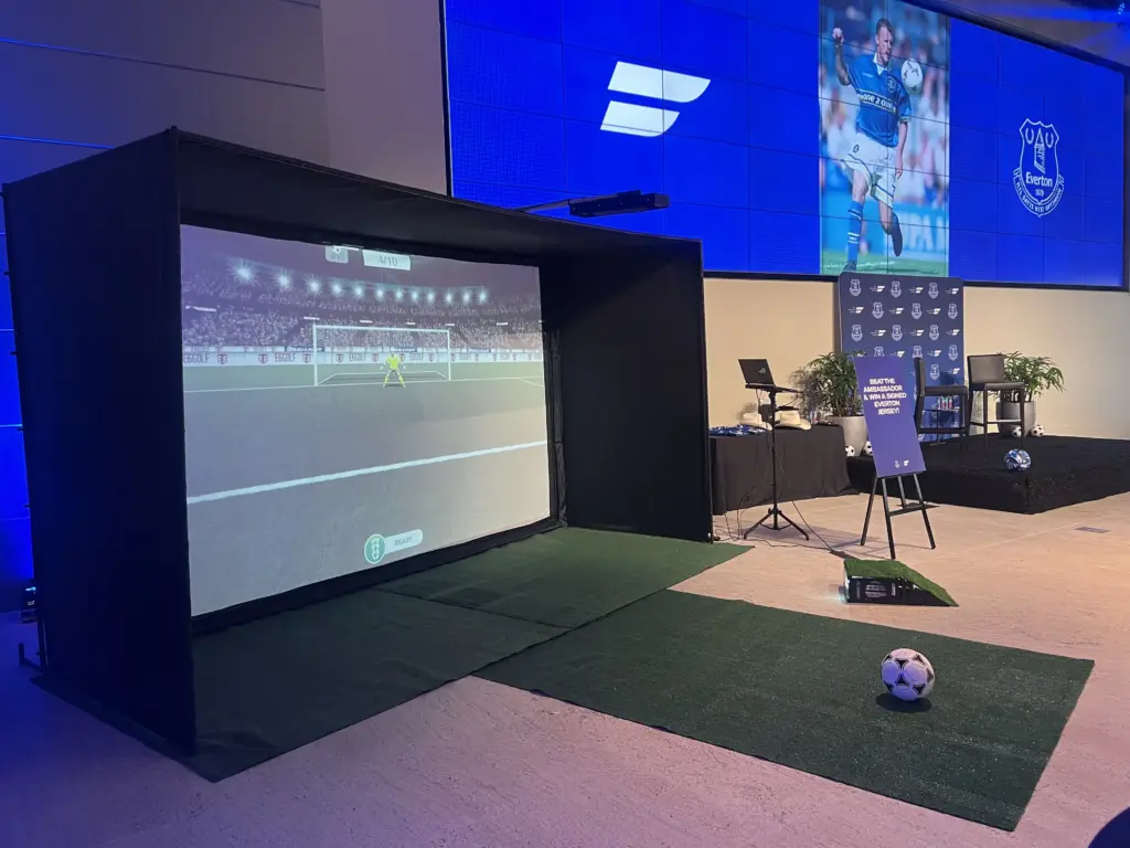 Soccer simulator with a penalty game next to an Everton video wall at The Friedkin Group campus in Houston