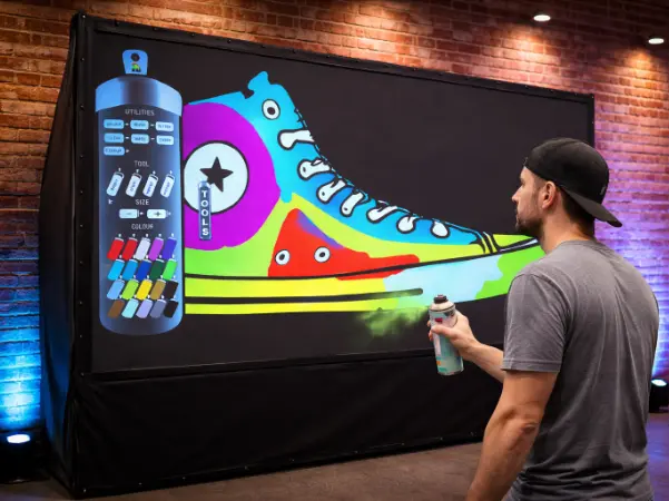 Guest spray-painting a giant sneaker on an Air Graffiti Wall rental at an event