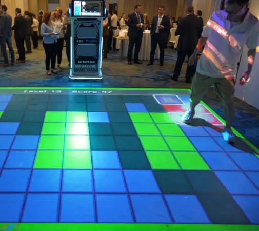 Interactive floor game rental with glowing LED tiles at a busy evening event