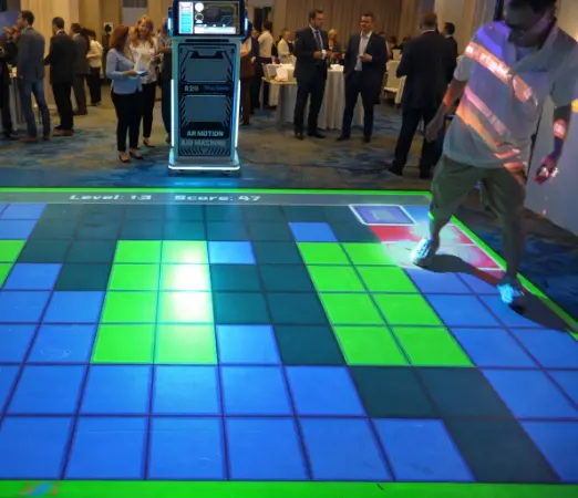 Guests crossing glowing floor tiles in a Floor is Lava game rental at an evening event